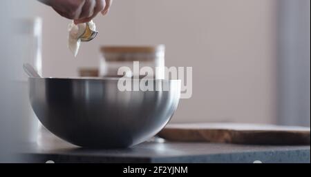 man making granola pour honey into steel bowl on kitchen countertop, wide photo Stock Photo