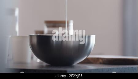 man making granola pour honey into steel bowl on kitchen countertop, wide photo Stock Photo