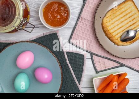 Colored Easter egg in plate on a breakfast table with jam and toasted bread. Stock Photo