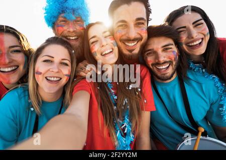 Football fans taking selfie during the soccer match event at stadium - Young people having fun supporting favorite club - Sport entertainment concept Stock Photo