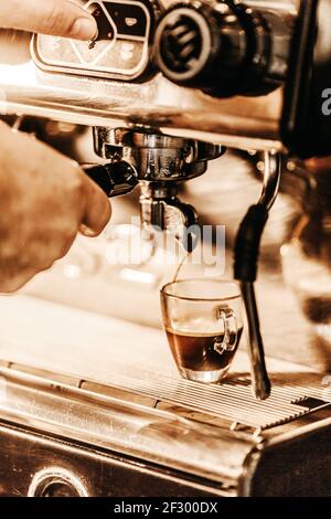 A vertical shot of a barista preparing hot tasty coffee on a coffee machine Stock Photo