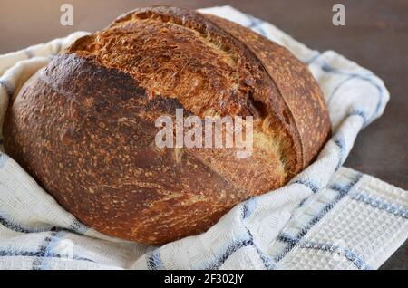 Freshly baked loaf of sourdough bread on a kitchen towel close-up Stock Photo