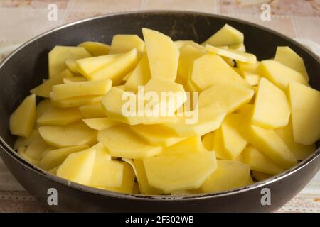 Potatoes cut into slices lie in a frying pan.Prepared vegetables for roasting Stock Photo