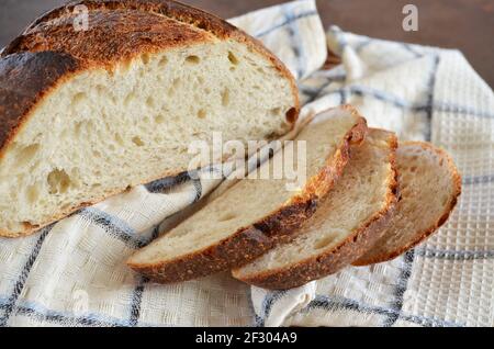 Sliced sourdough bread with a crisp crust on a kitchen towel close-up, selective focus Stock Photo