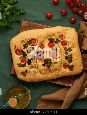 Food art. Focaccia, Flatbread with tomatoes,on dark green linen textile tablecloth. Top view Stock Photo