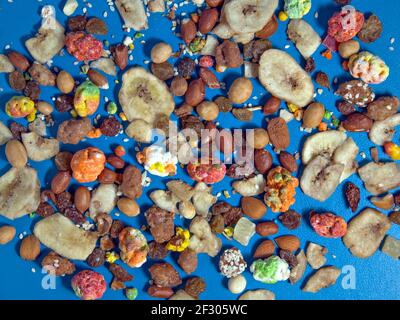 Colorful nuts are scattered on blue surface of table. Stock Photo