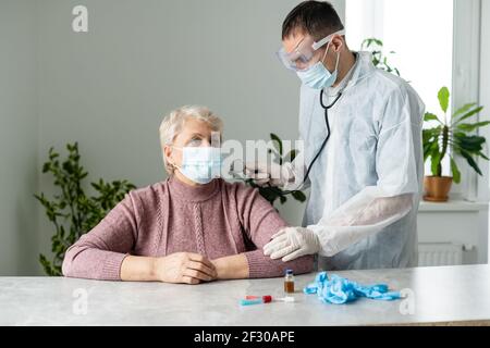 In modern private clinic doctor is listening heart of senior patient sitting on hospital bed. Healthcare medical medicine consultation, using Stock Photo