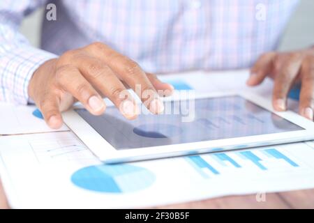young man working on digital tablet at office desk, using self created chart  Stock Photo