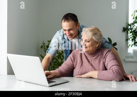 Portrait of a senior woman and a man in front of a laptop computer Stock Photo