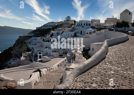 Panoramic view of the village of Oia on the island of Santorini, Greece. Traditional rocky streets with houses and churches with blue domes above the Stock Photo