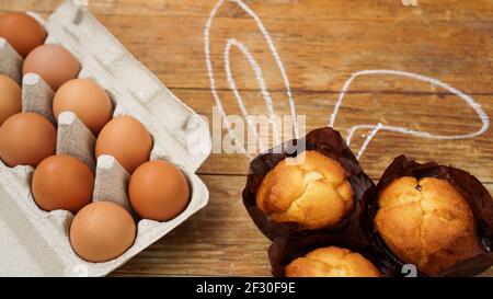 Homemade muffin with painted rabbit ears. Muffin and eggs on a wooden Stock Photo