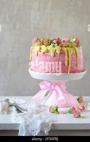 Festive pink strawberry buttercream cake with yellow chocolate glazing and roses Stock Photo