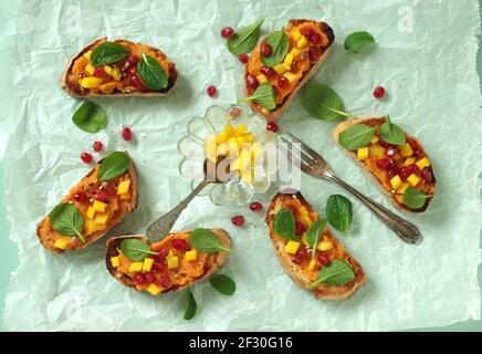 Crostini with sweet potato puree, mango, chinese baby spinach and pomegranate Stock Photo