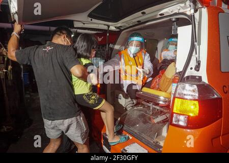 Denpasar, Bali, Indonesia. 14th Mar, 2021. A municipal worker and health workers to help a child to get into the ambulance. These child's mother is about to give birth amid night of Nyepi. Nyepi is the Balinese Hindu holiday of self-reflection in which all activities are stopped and people are not allowed to get outside with all the lights kept low, no working and no pleasures. (Credit Image: © Dicky BisinglasiZUMA Wire) Credit: ZUMA Press, Inc./Alamy Live News Stock Photo