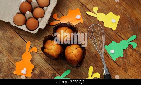 Homemade muffin with paper rabbits. Muffin and eggs on a wooden background Stock Photo
