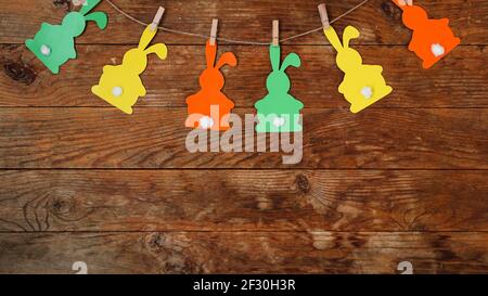Easter background. Garland of paper rabbits on a wooden background. Stock Photo