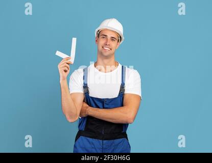 Handsome worker man in coveralls and hard hat holding check mark symbol Stock Photo