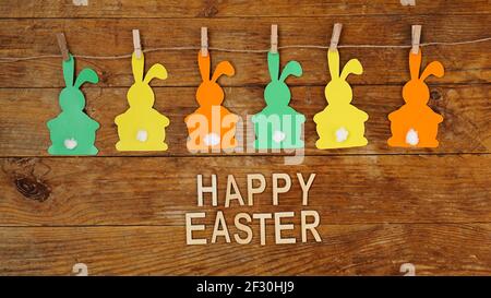 Happy Easter background. Garland of paper rabbits on a wooden background. Stock Photo