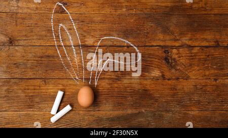 Egg on a wooden background. Chalk-drawn ears. Top view and place for text Stock Photo