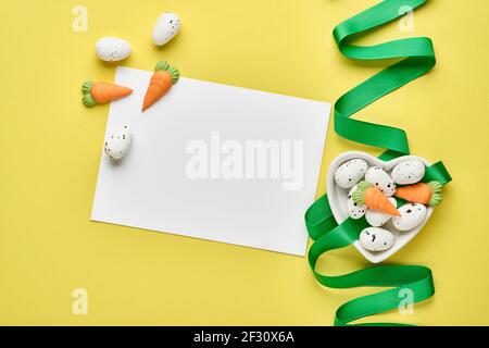 Easter spring greeting card with gift box with green ribbon, eggs and sweet carrot on pink background with place for text. Top view. Stock Photo