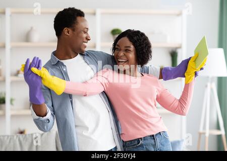 Cheerful african american couple dancing while cleaning apartment Stock Photo