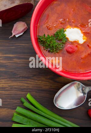 Red borscht soup with parsley in brown bowl on wooden. Stock Photo
