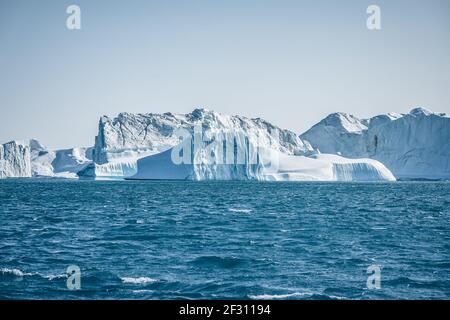 Bright sunny day in Antarctica. Full calm and reflection of icebergs in deep clear water. Travel by the ship among ices. Snow and ices of the Stock Photo