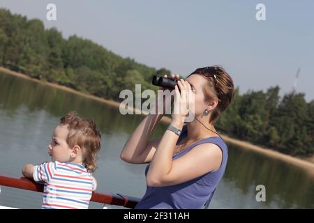 Mother looking through binoculars on Volga river Stock Photo