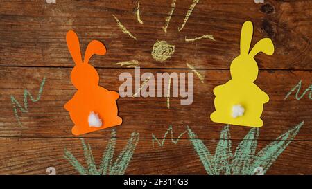 Two Easter bunnies made of paper. Drawn with colored chalk grass and sun Stock Photo