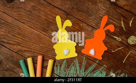 Two Easter bunnies made of paper. Drawn with colored chalk grass and sun Stock Photo