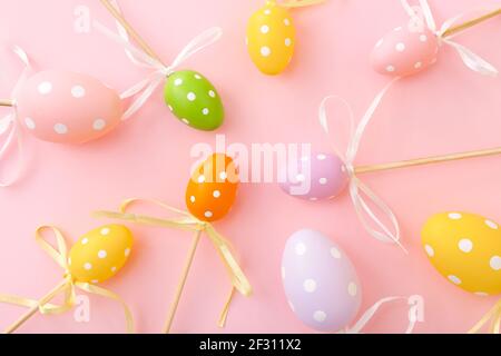 Colorful Easter eggs on sticks on pink background. Festive Easter holiday greeting card Stock Photo