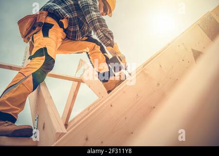 Caucasian Contractor Worker in His 40s with Drill Driver in His Hand. Carpenter Working on Wooden House Skeleton Frame Roof Section. Construction Indu Stock Photo
