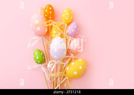 Colorful Easter eggs on sticks on pink background. Festive Easter holiday greeting card with copy space. Stock Photo