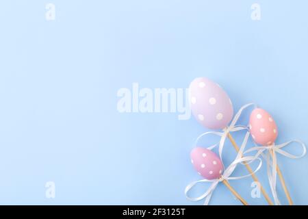 Colorful Easter eggs on sticks on blue background. Festive Easter holiday greeting card with copy space. Top view Stock Photo