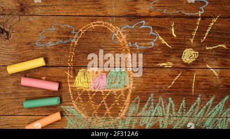 Drawing with crayons on a wooden background. Easter eggs in a basket Stock Photo