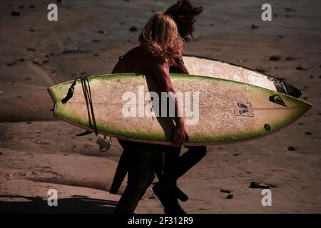 Two male surfers with their surfboards heading towards the waves. Stock Photo