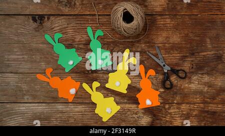 Easter bunnies made of paper on a wooden background. Create a decor for easter Stock Photo