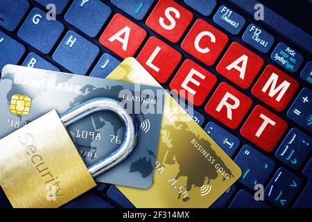 Scam Alert in red keys on high-tech computer keyboard background with security engraved lock on fake credit cards. Concept of Internet security, data Stock Photo