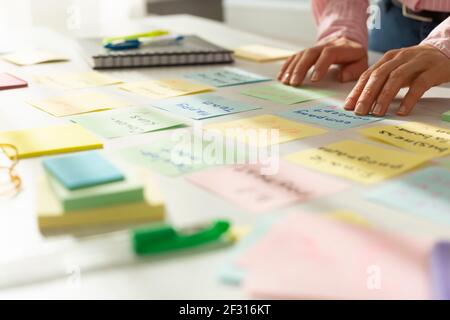 Business woman's hands write notes on stickers on the desktop. Stock Photo