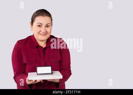 Smiling business lady , large woman, holding diary with business card holder, visiting cards, an empty white business card on grey background. Blank Stock Photo