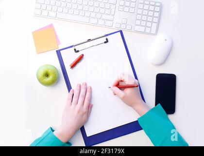 Top view of womans hand holding pen on white paper with clipboard and ready to writing. Isolated on white background. Stock Photo