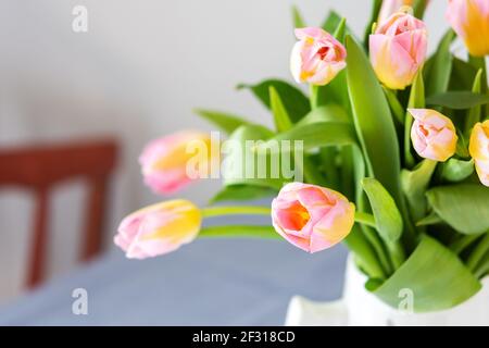 Beautiful spring bouquet of pink tulips in a jug on the table, flowers in a home interior Stock Photo