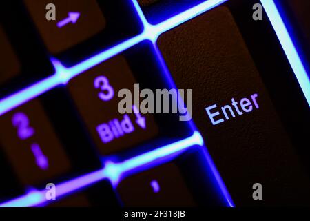 Macro closeup of blue illuminated enter key on computer keyboard (selective focus on left part of letter n) Stock Photo