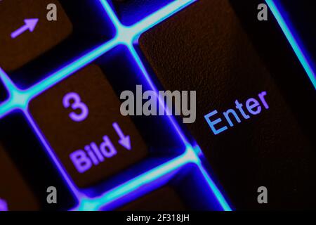 Macro closeup of blue illuminated enter key on computer keyboard (selective focus on left part of letter n) Stock Photo