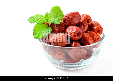 Dried Jujube, Chinese dried red date fruit with Mint leaves in glass cup isolated on white,herbal fruits. It have more vitamin C Which helps fight fre Stock Photo
