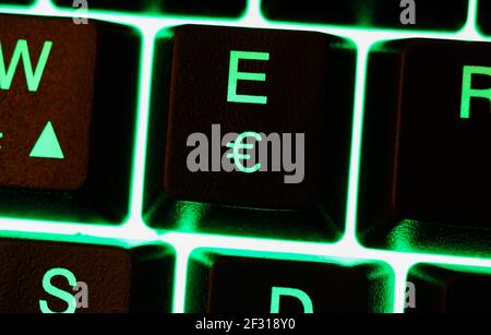 Macro closeup of green illuminated keys with letter e and euro currency sign on computer keyboard Stock Photo