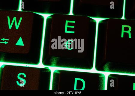 Macro closeup of green illuminated keys with letter e and euro currency sign on computer keyboard Stock Photo