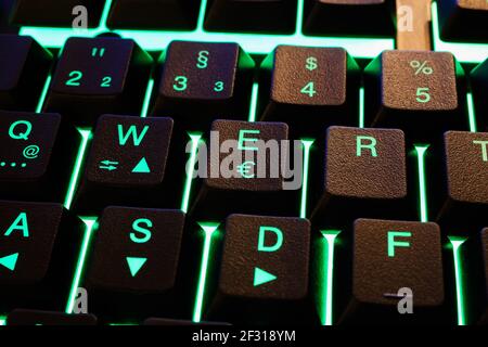 Closeup of isolated green illuminated computer keyboard keys (focus on key with letter E and euro currency symbol) Stock Photo