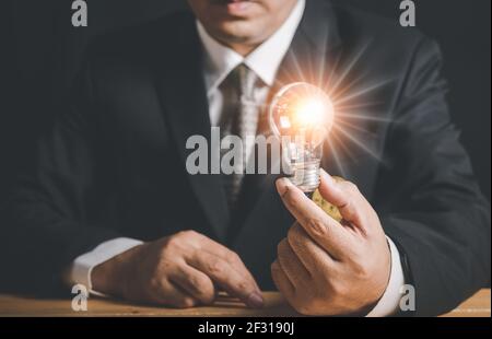 Hand of businessman holding illuminated light bulb, idea, innovation and inspiration concept, copy space. Stock Photo