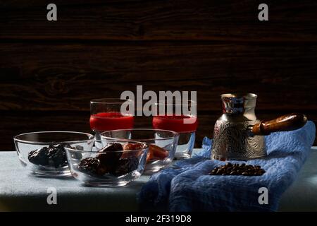 Coffee pot (Cezve), coffee beans, two glasses of coffee, dry apricot and dry plum. Stock Photo